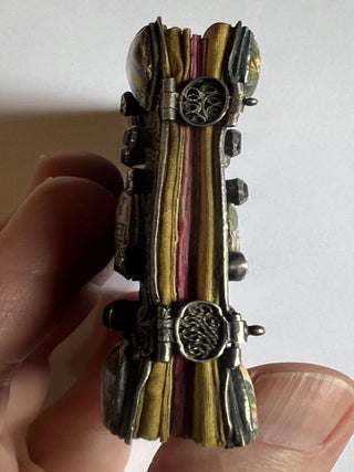 A miniature silver binding decorated with painted enamel plaques and glass &ldquo;jewels.&rdquo;