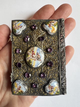 A miniature silver binding decorated with painted enamel plaques and glass &ldquo;jewels.&rdquo;